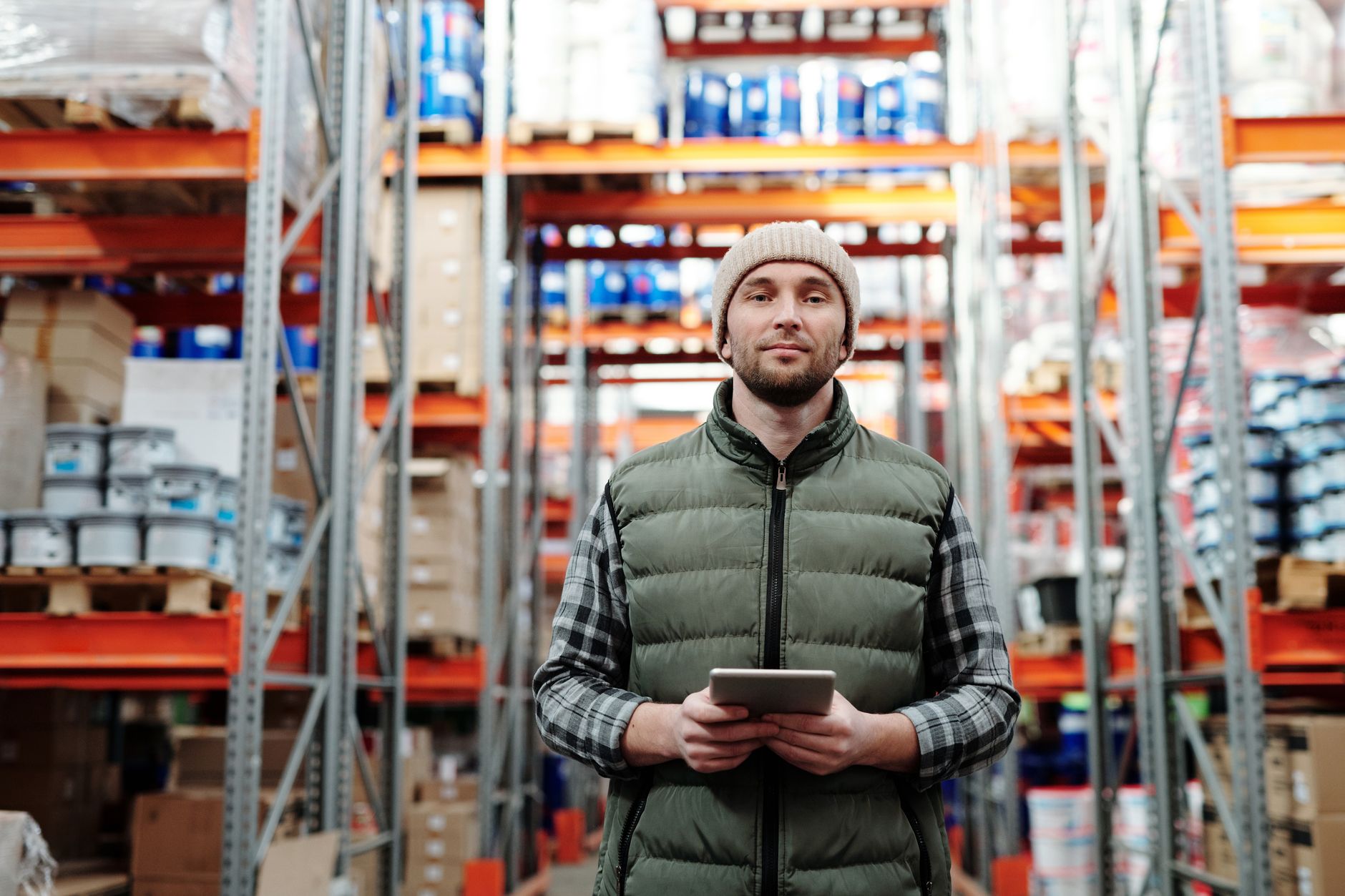 Un homme tenant une tablette numérique au milieu des rayonnages d’un entrepôt de stockage.
